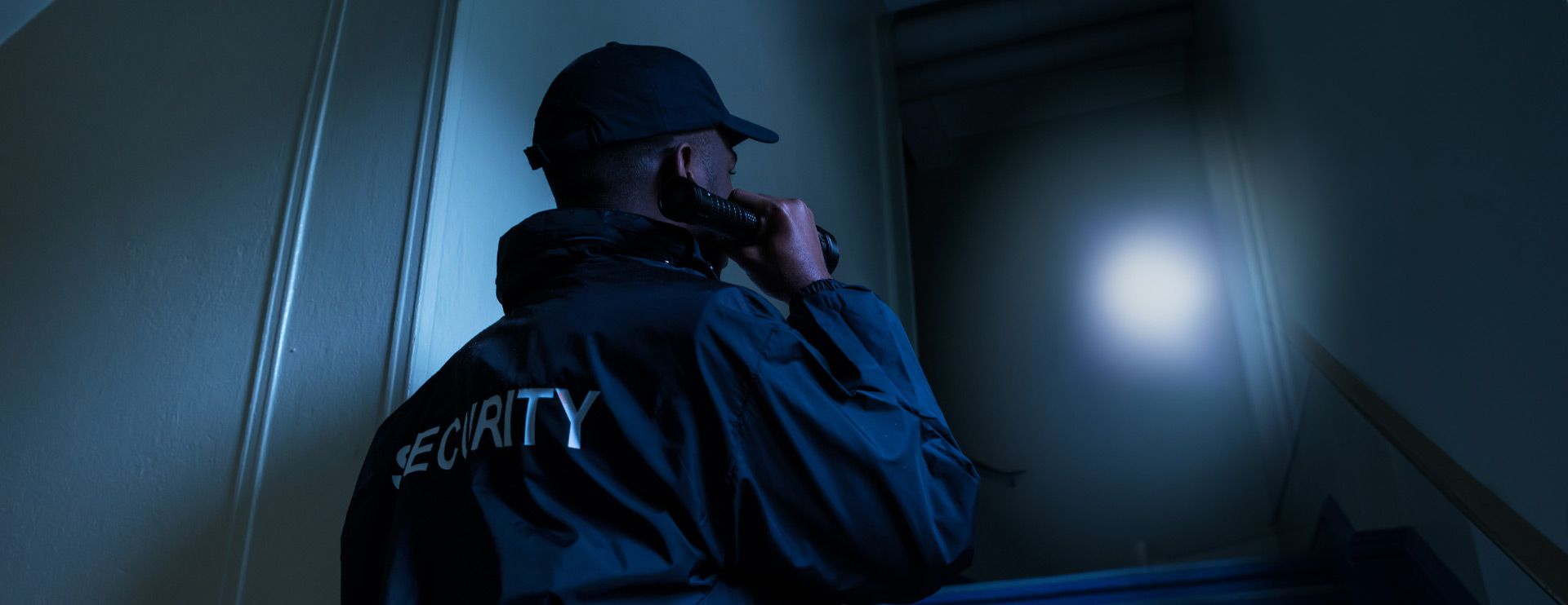 Ein Sicherheitsmitarbeiter leuchtet im Dunkeln mit einer Taschenlampe.