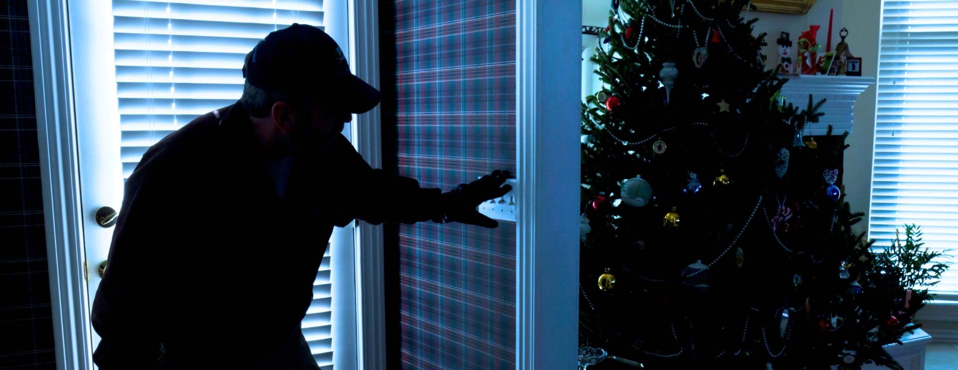 Ein Einbrecher schleicht um die Ecke in einem Haus und entdeckt einen Weihnachtsbaum