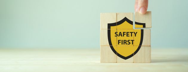 Aus neun kleinen Bausteinen, die übereinander und nebeneinander gestapelt wurden, entsteht eine gelb-schwarze Abbildung auf der „Safety First“ steht