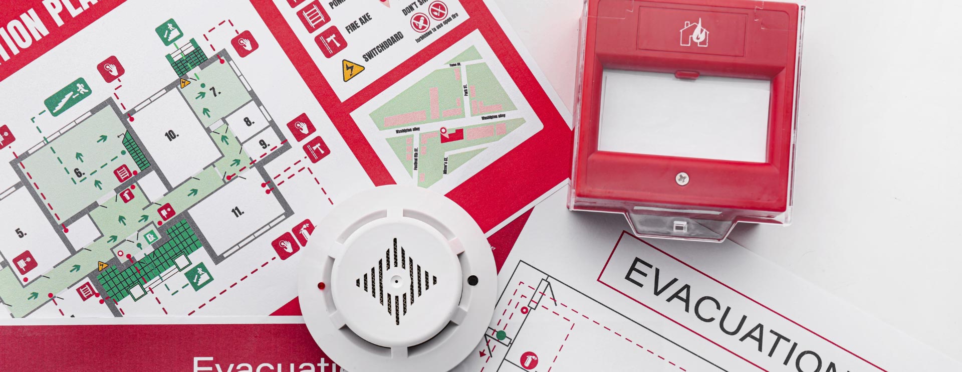 Feuermelder und Evakuierungspläne liegen auf weißem Tisch.