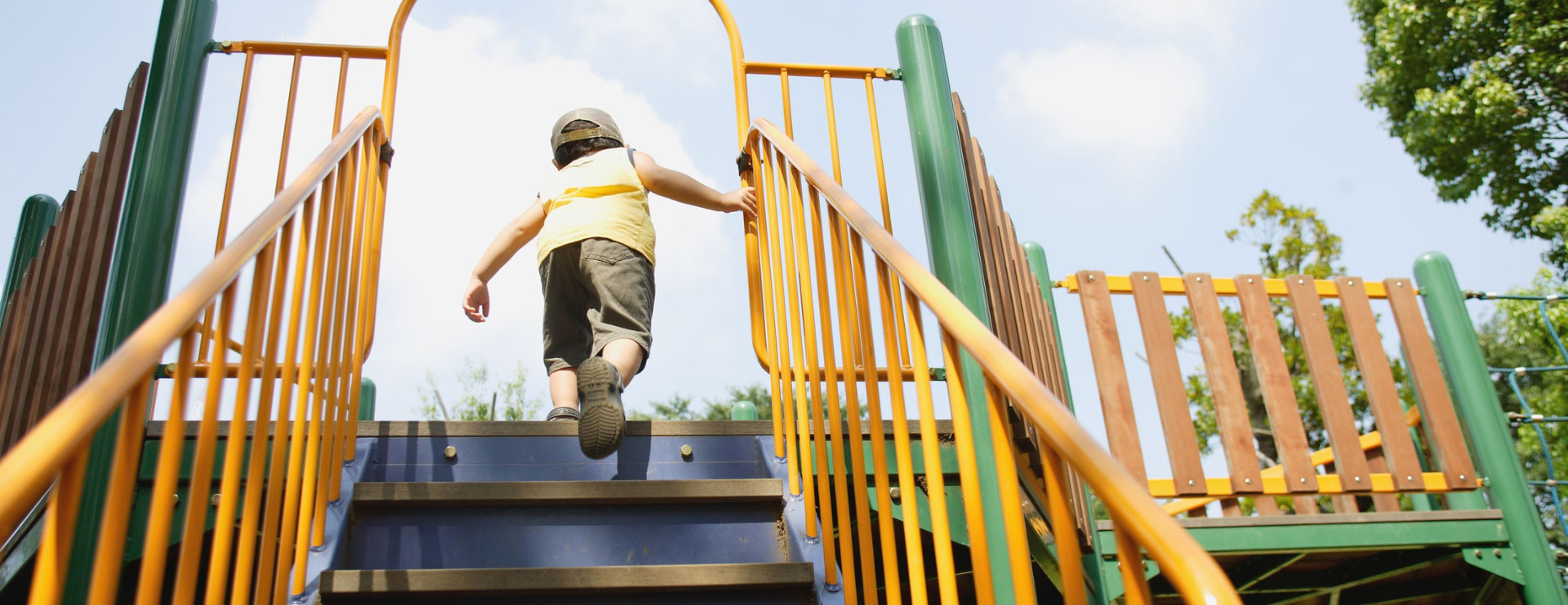 Ein Kind steigt die Treppen eines bunten Klettergerüstes hinauf.